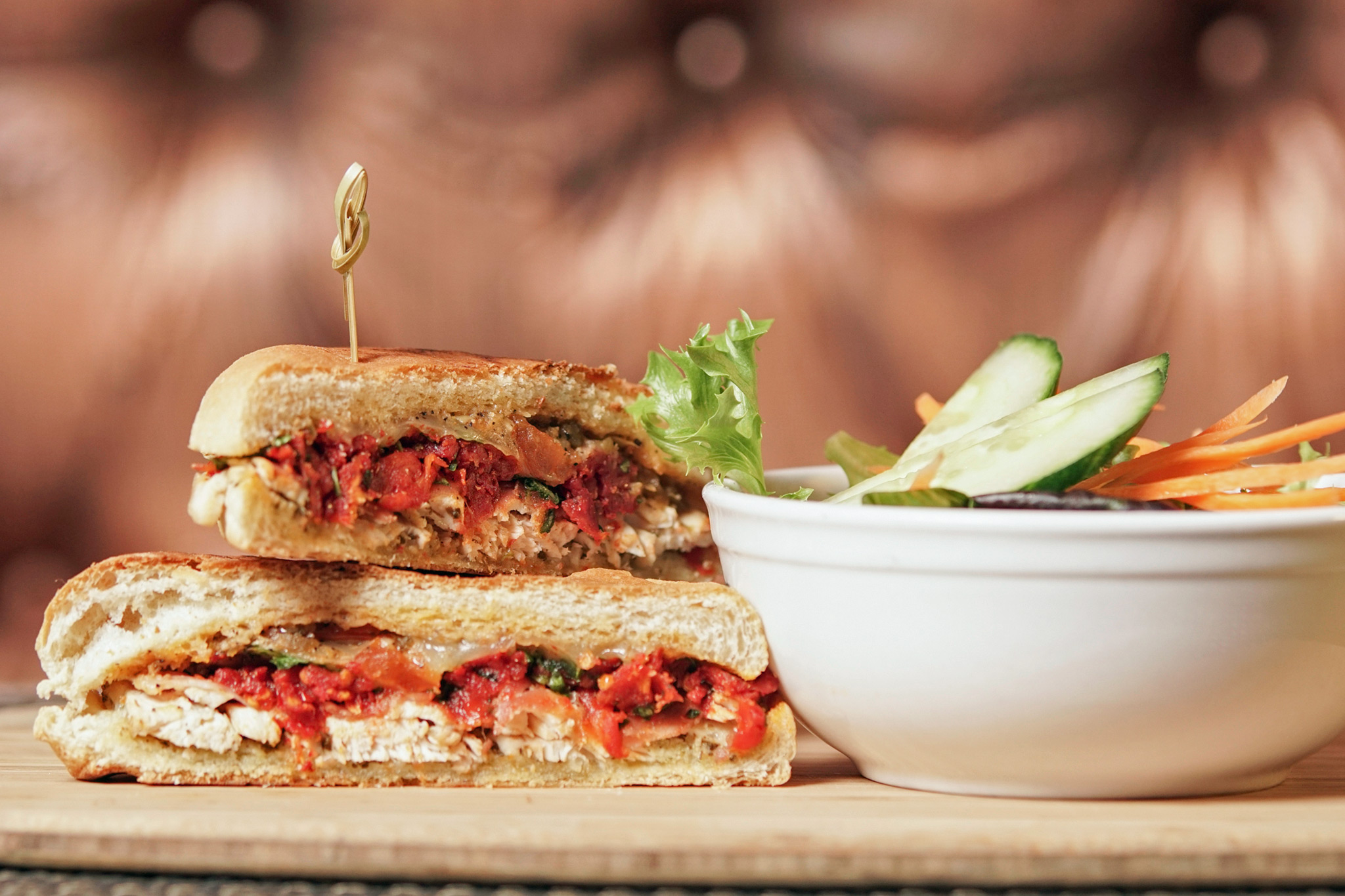 Chicken Panini - herb marinated grilled chicken breast, basil pesto, arugula and sun dried tomato relish, Tryst pepper sauce, toma cheese, prosciutto, ciabatta bun