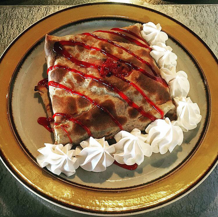 Granola crêpe is filled with crunchy granola, fresh mixed berries, raspberry coulis and topped with whipped cream