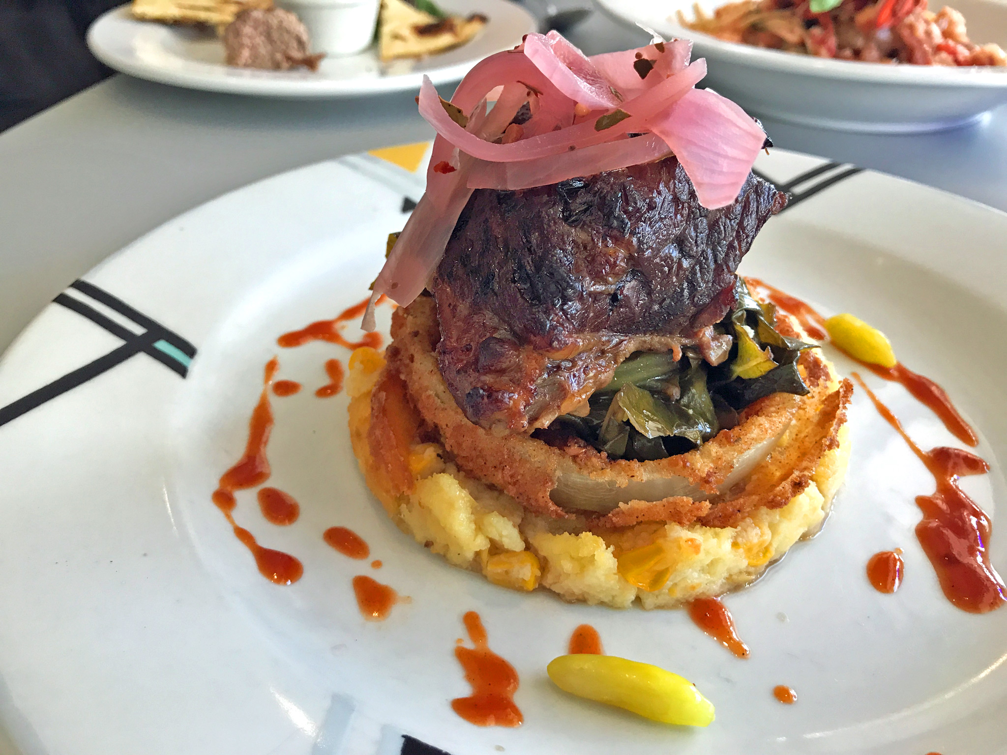 Braised short ribs, smokey collard greens, corn spoonbread, pickled onions, onion ring, and house-made BBQ sauce