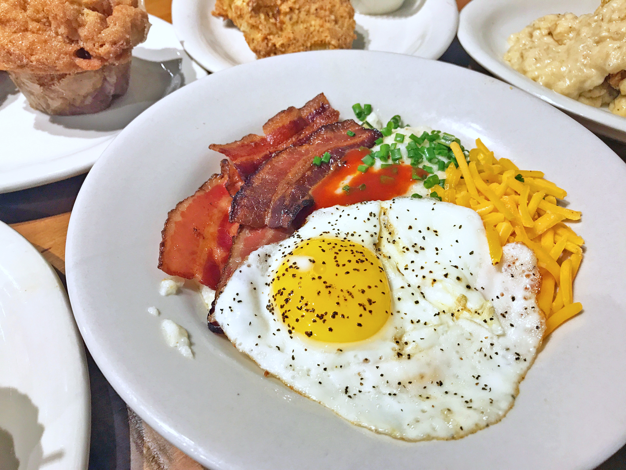 Sunny Side Up Fried Eggs In Heavy Duty Teflon Frying Pan With Pork Bacon  Rashers On Cutting Board Set On Old Cracked Wooden Picnic Table Stock Photo