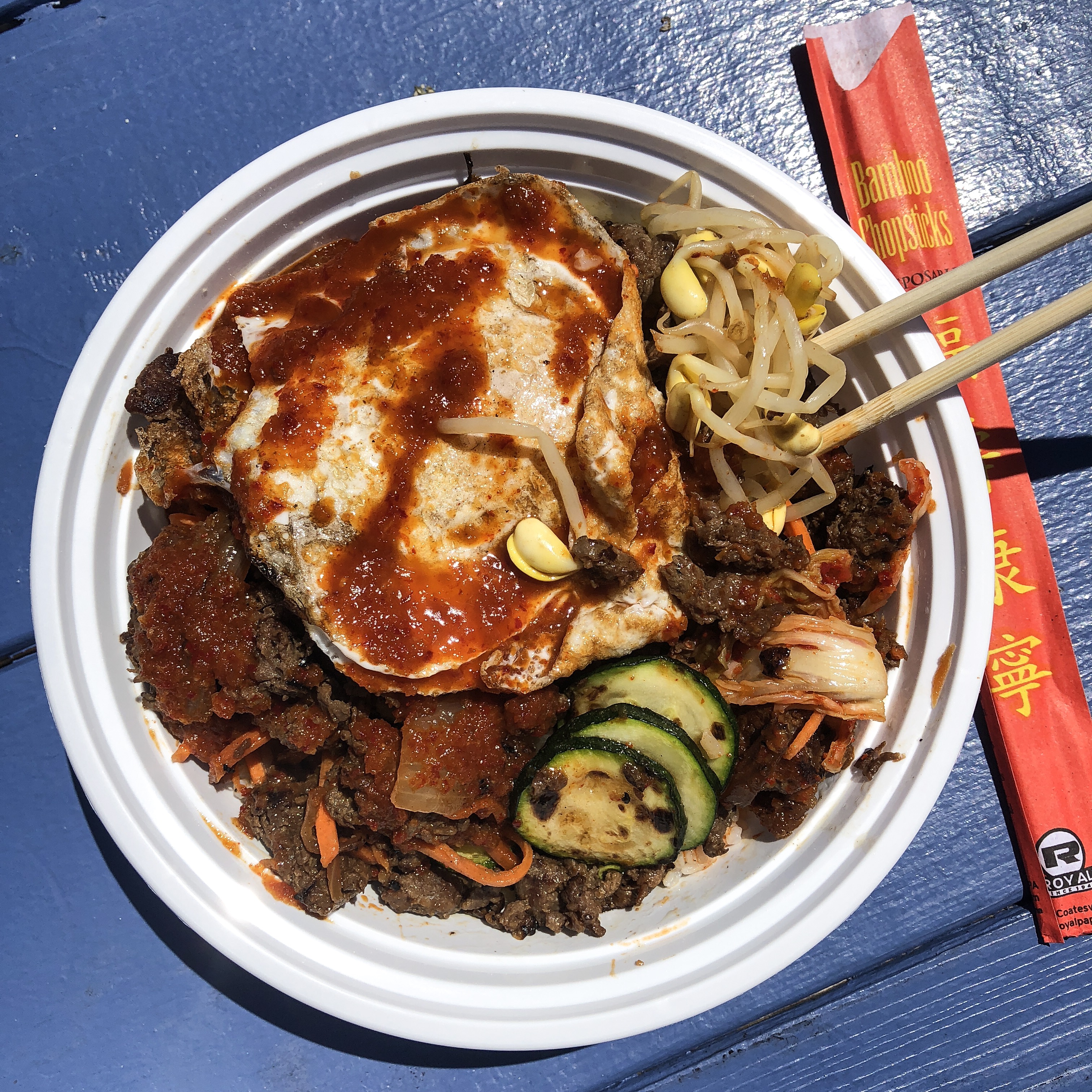 Bop Bowl with Beef Bulgogi, Steamed Rice, Carrots, Zucchini, Sprouts and Kimchi topped with Mild Bop Sauce and an Ovreasy Egg.