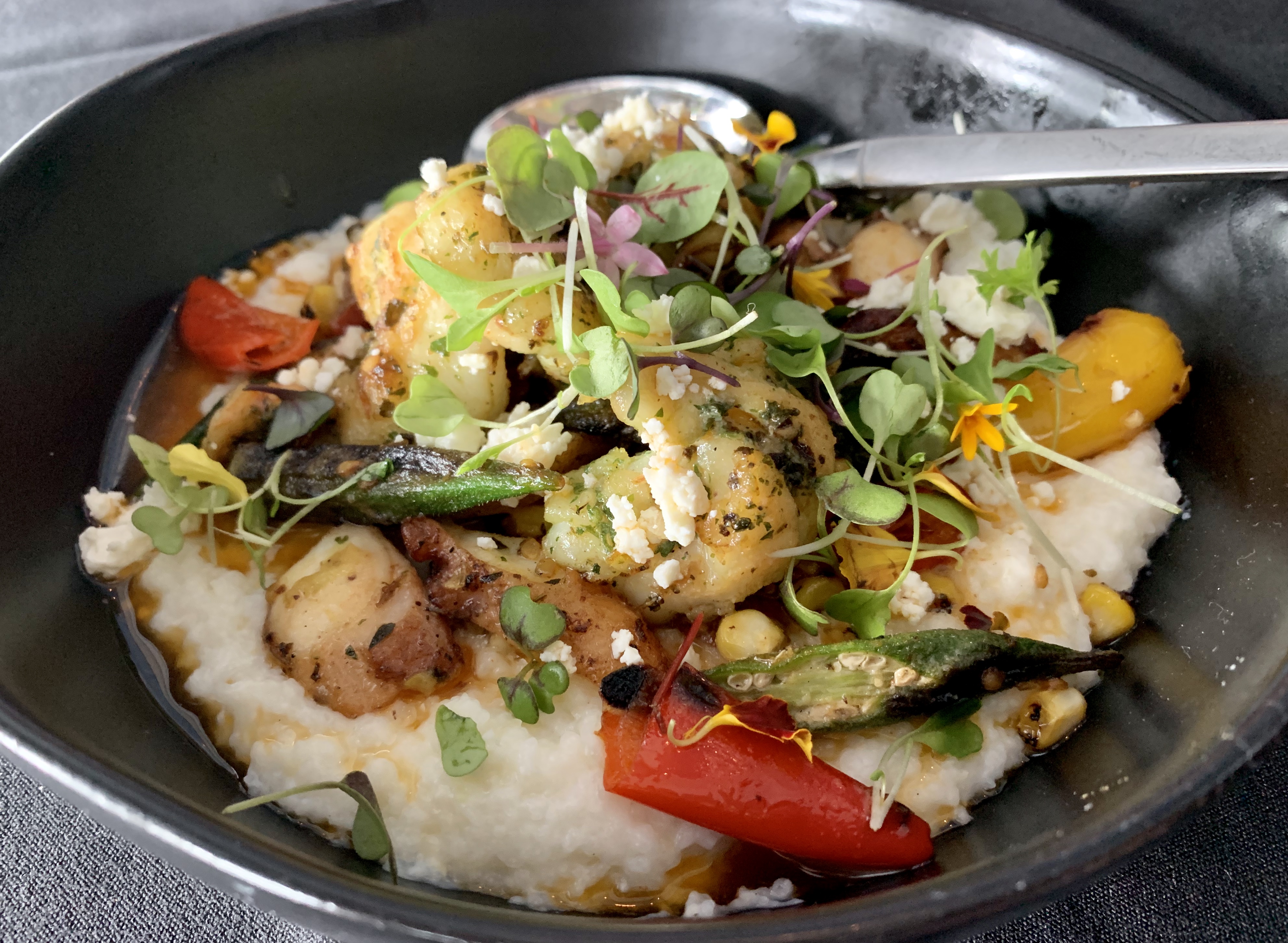 Shrimp and Octopus Grits with Charred Corn, Okra, Roasted Peppers, Tomatoes, Feta and Lobster Butter. Offered on the Brunch menu.