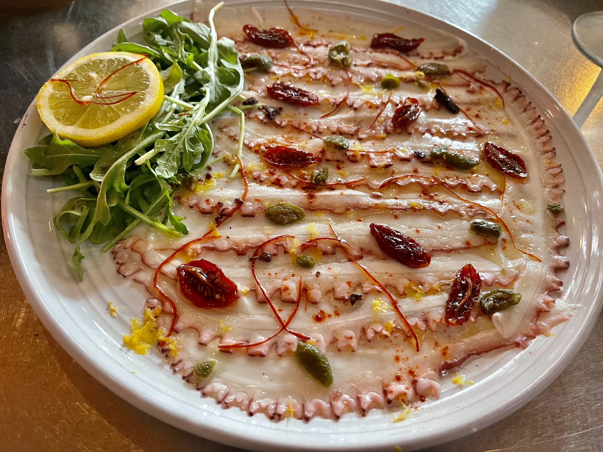 https://stpetersburgfoodies.com/wp-content/uploads/2022/06/Renzos-Carpaccio-of-Octopus-Nikkei-tiradito-of-octopus-dressed-with-evoo-and-fresh-lemon.jpeg