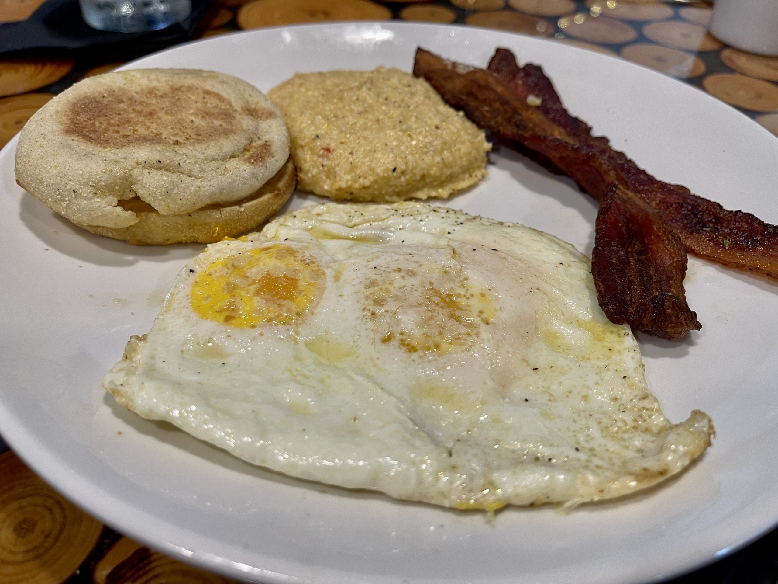 Sunny Side Up Fried Eggs In Heavy Duty Teflon Frying Pan With Pork Bacon  Rashers On Cutting Board Set On Old Cracked Wooden Picnic Table Stock Photo