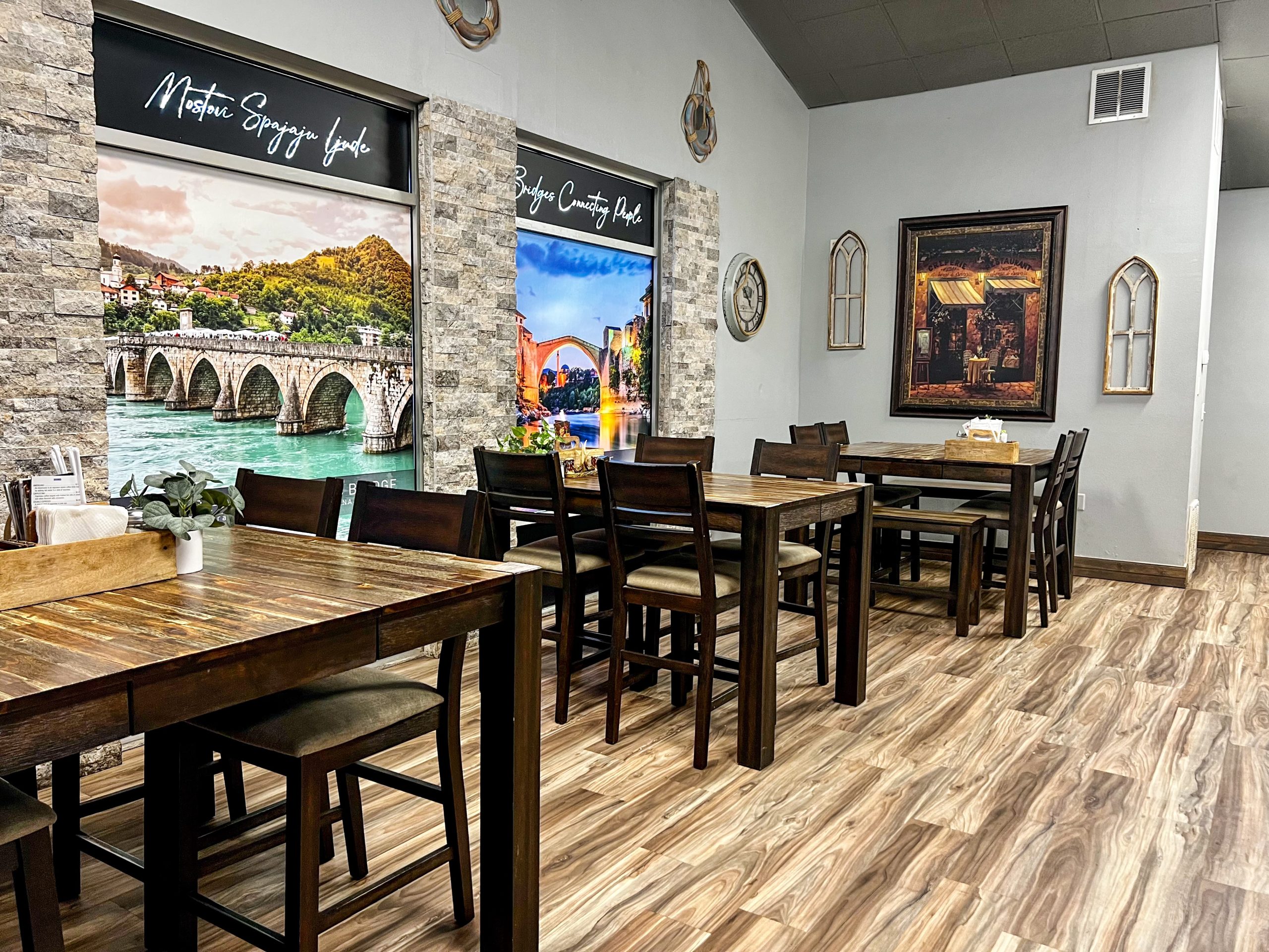 The bright dining room of Serbian Mediteran Restaurant with a handful of tables in and outside
