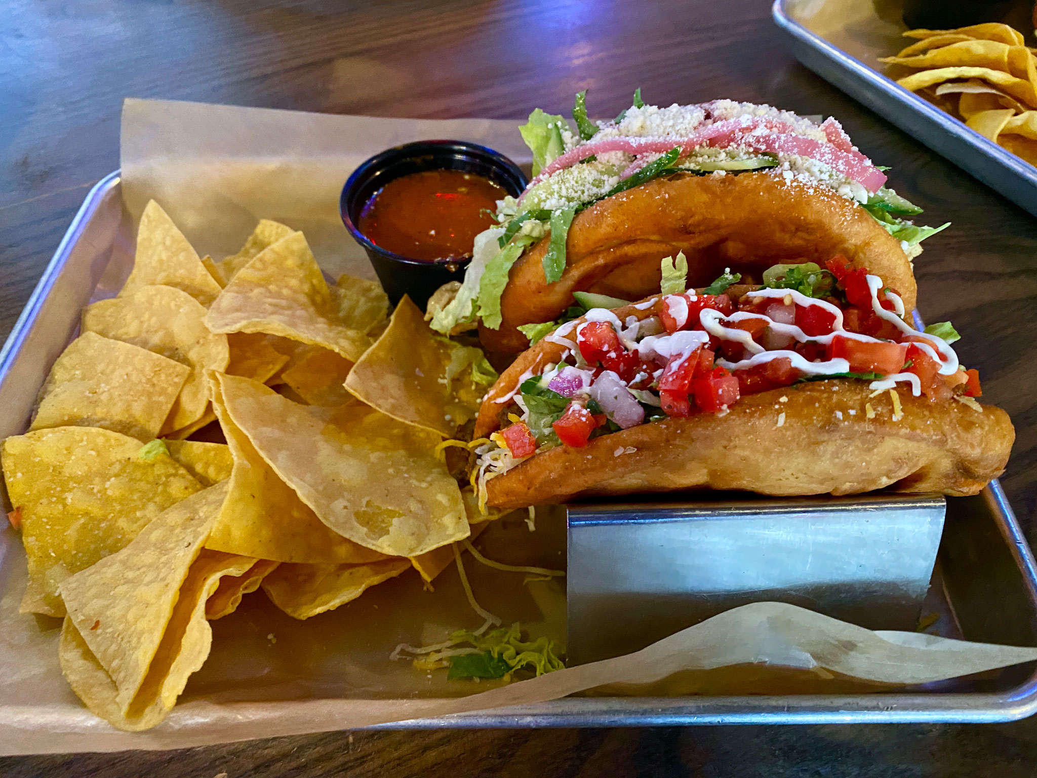Chalupas - Shwarmagedon and 90's Beef Cake Back: Shwarmagedon - Shawarma chicken, fluffy garlic sauce, cotija, cucumbers, tomatoes, lettuce, pickled red onions, cilantro. Front: 90's Beef Cake - Seasoned ground beef, jack and cheddar, pico de gallo, sour cream, crisp lettuce.